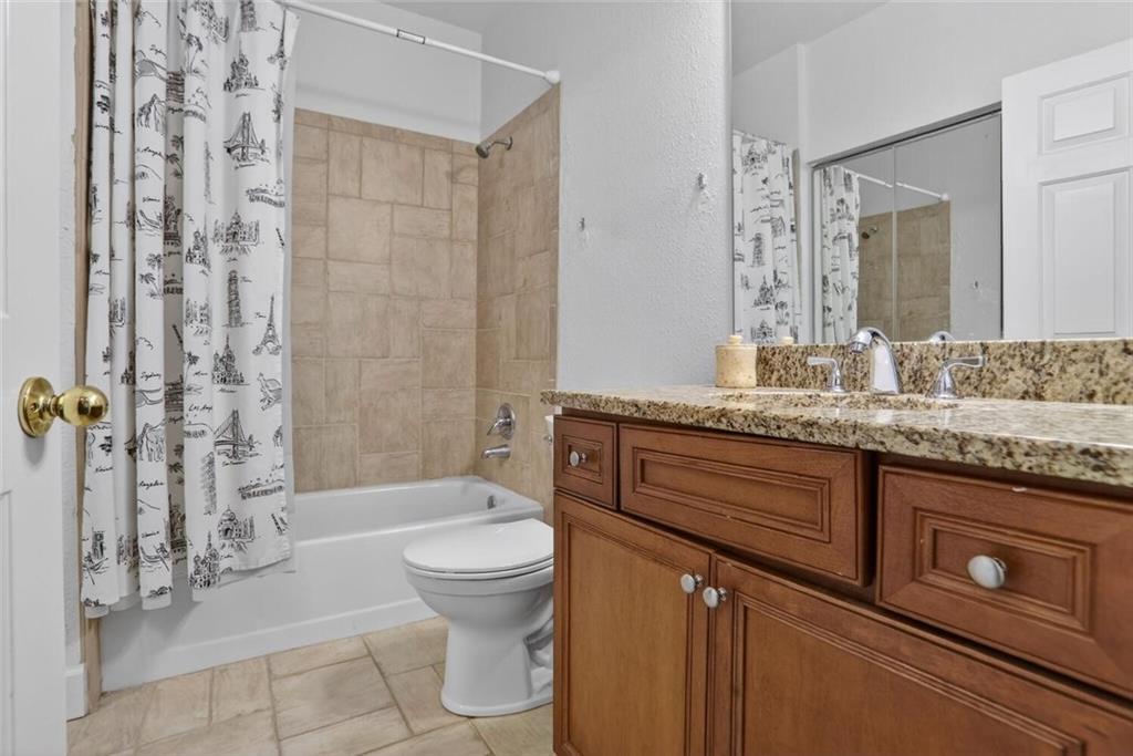 2921 Lenox Road Northeast, Unit 413 Atlanta, GA 30324 - Photo 13 of 36 a bathroom with a granite countertop sink a toilet a mirror and shower