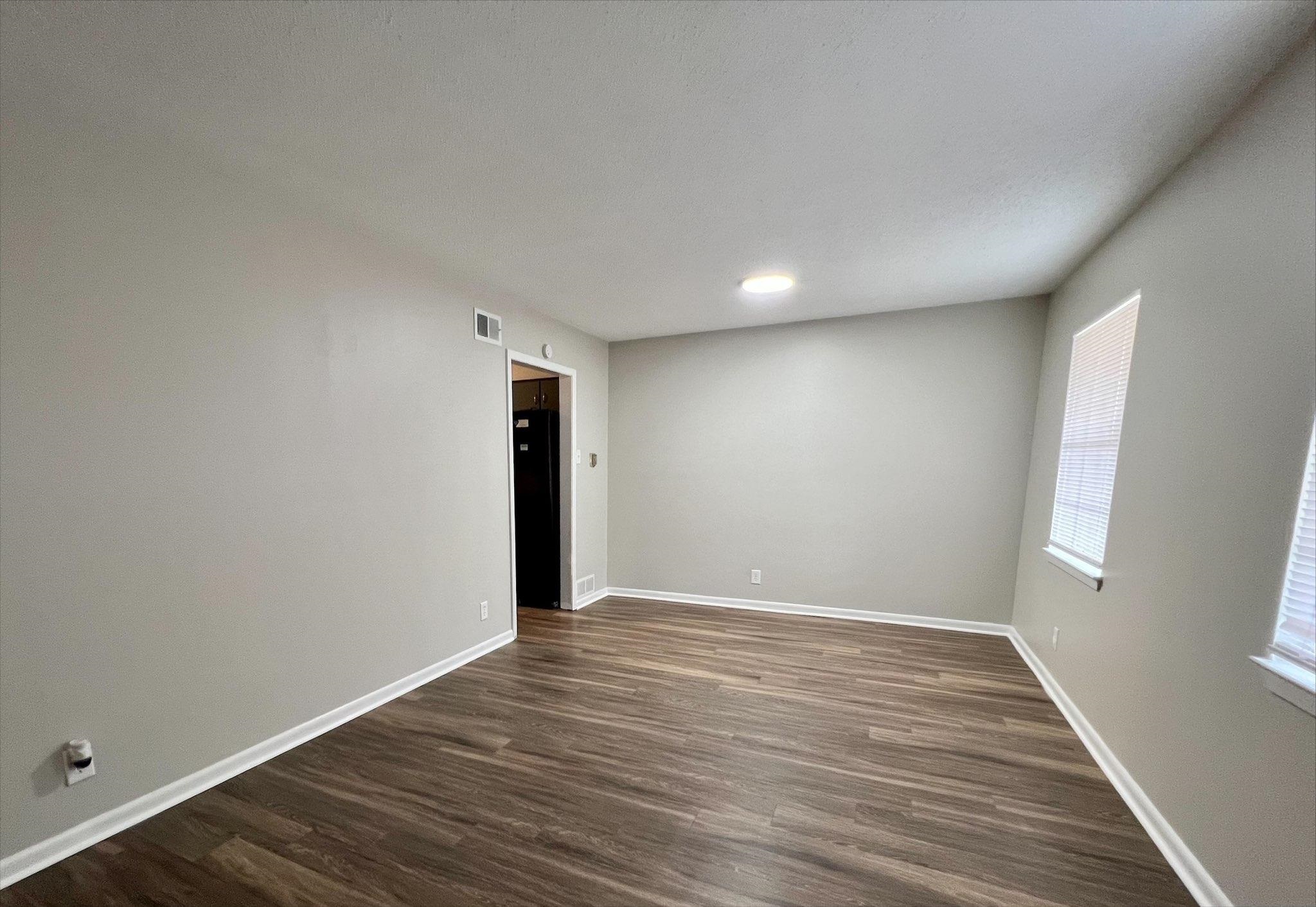 3831 Millbranch Road Memphis, TN 38116 - Photo 9 of 12 a view of an empty room with wooden floor and window