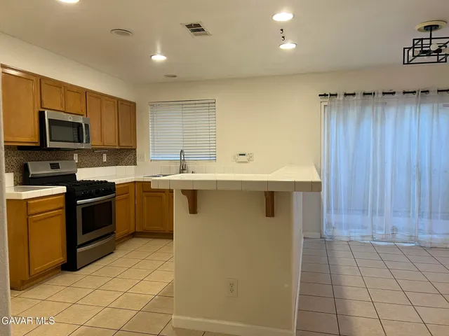 a kitchen with stainless steel appliances granite countertop a stove a sink and a microwave