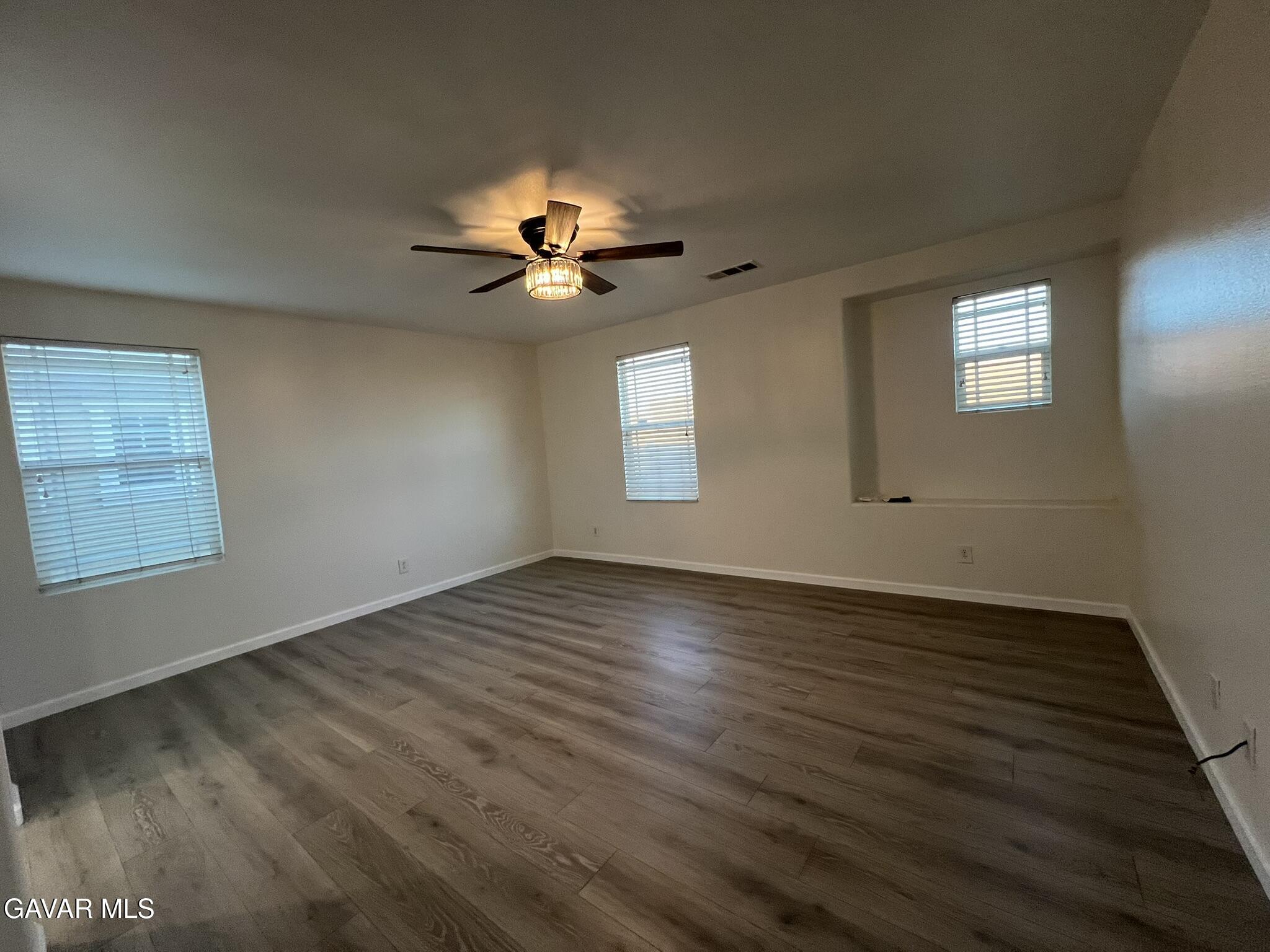 2649 Torres Court Palmdale, CA 93550 - Photo 17 of 33 an empty room with wooden floor and chandelier fan