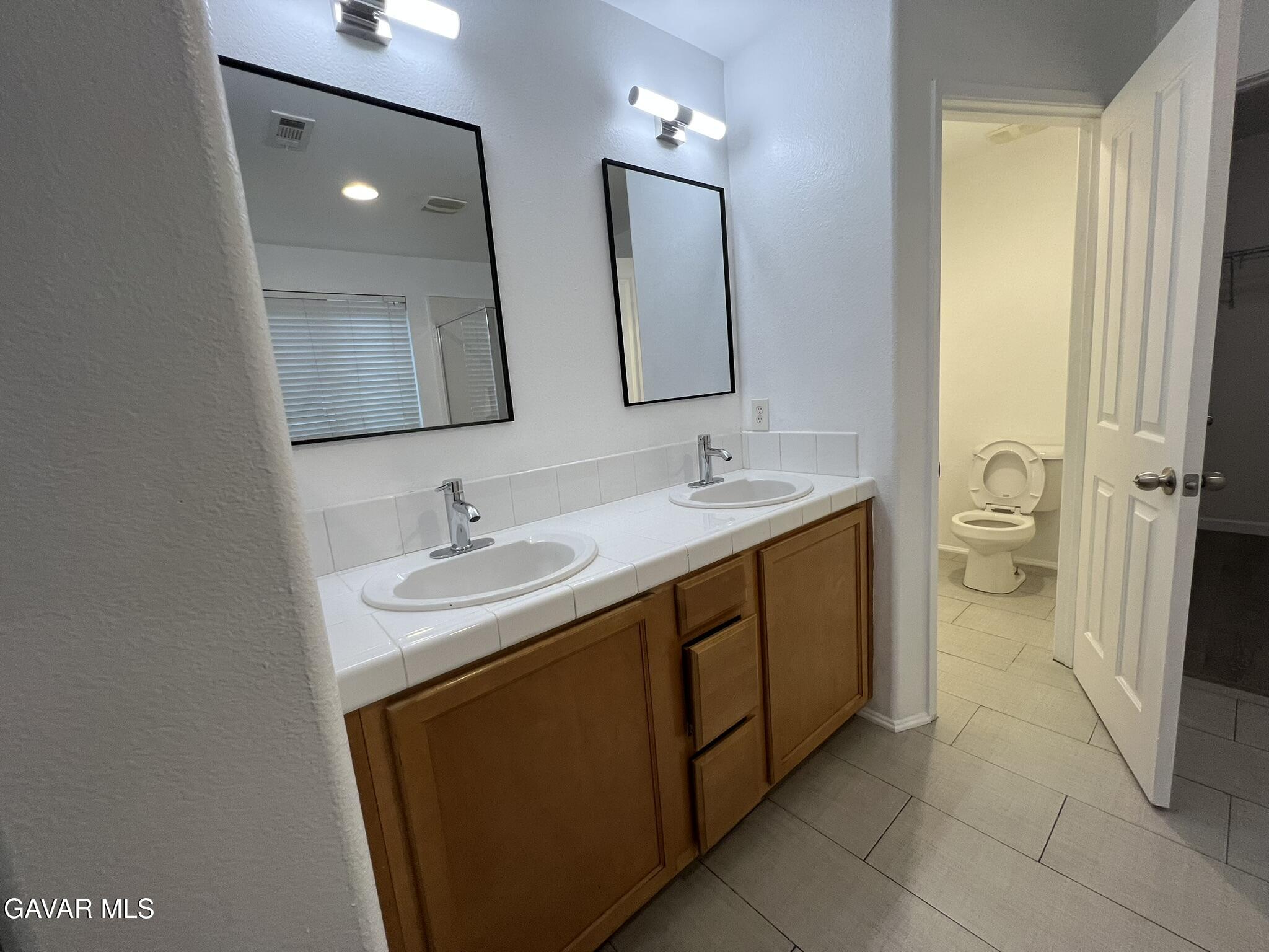 2649 Torres Court Palmdale, CA 93550 - Photo 21 of 33 a bathroom with a double vanity sink toilet and mirror