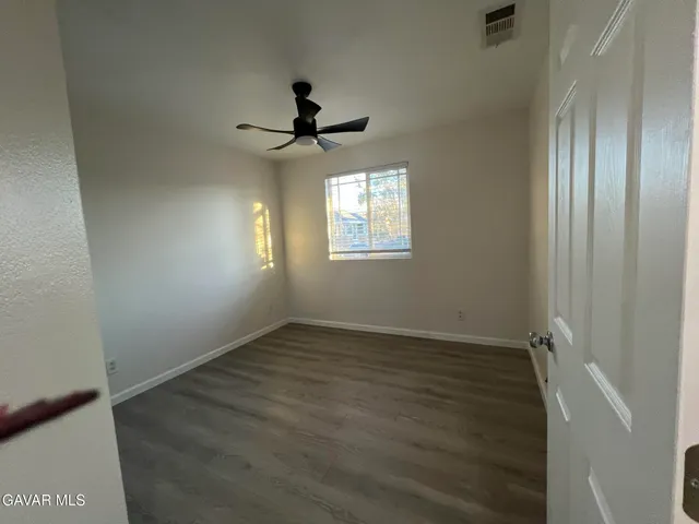 an empty room with wooden floor fan and windows