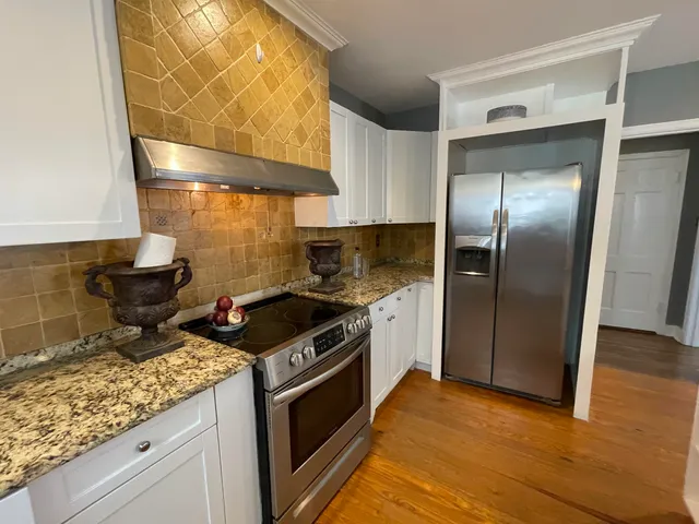 a kitchen with granite countertop a stove and a wooden floor