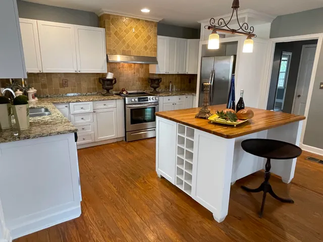 a kitchen with stainless steel appliances granite countertop wooden cabinets a stove a sink and a microwave