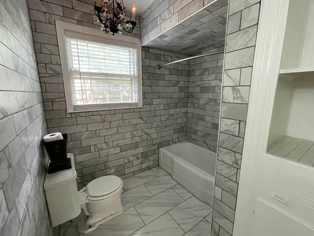 a bathroom with a toilet a window and tub