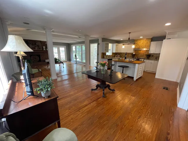 a living room with furniture and a dining table with wooden floor