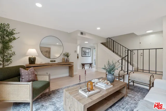 a living room with furniture a mirror and a wooden floor