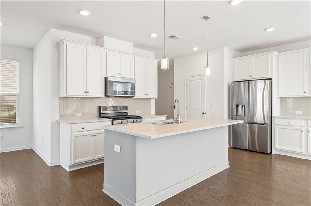 4734 Dewitt Drive Duluth, GA 30097 - Photo 11 of 31 a kitchen with stainless steel appliances granite countertop a sink a stove a refrigerator and island with wooden floor