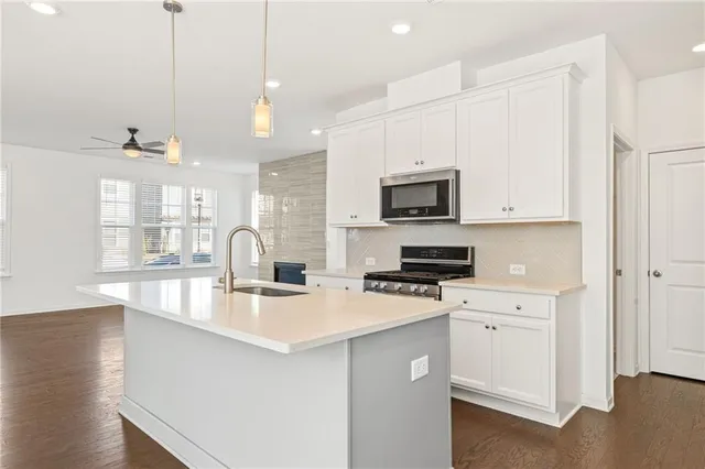 a kitchen with stainless steel appliances granite countertop a sink a stove and a wooden floors