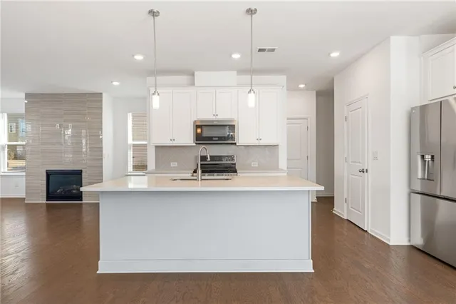 a large kitchen with stainless steel appliances granite countertop a stove a refrigerator a oven and a fireplace with wooden floor