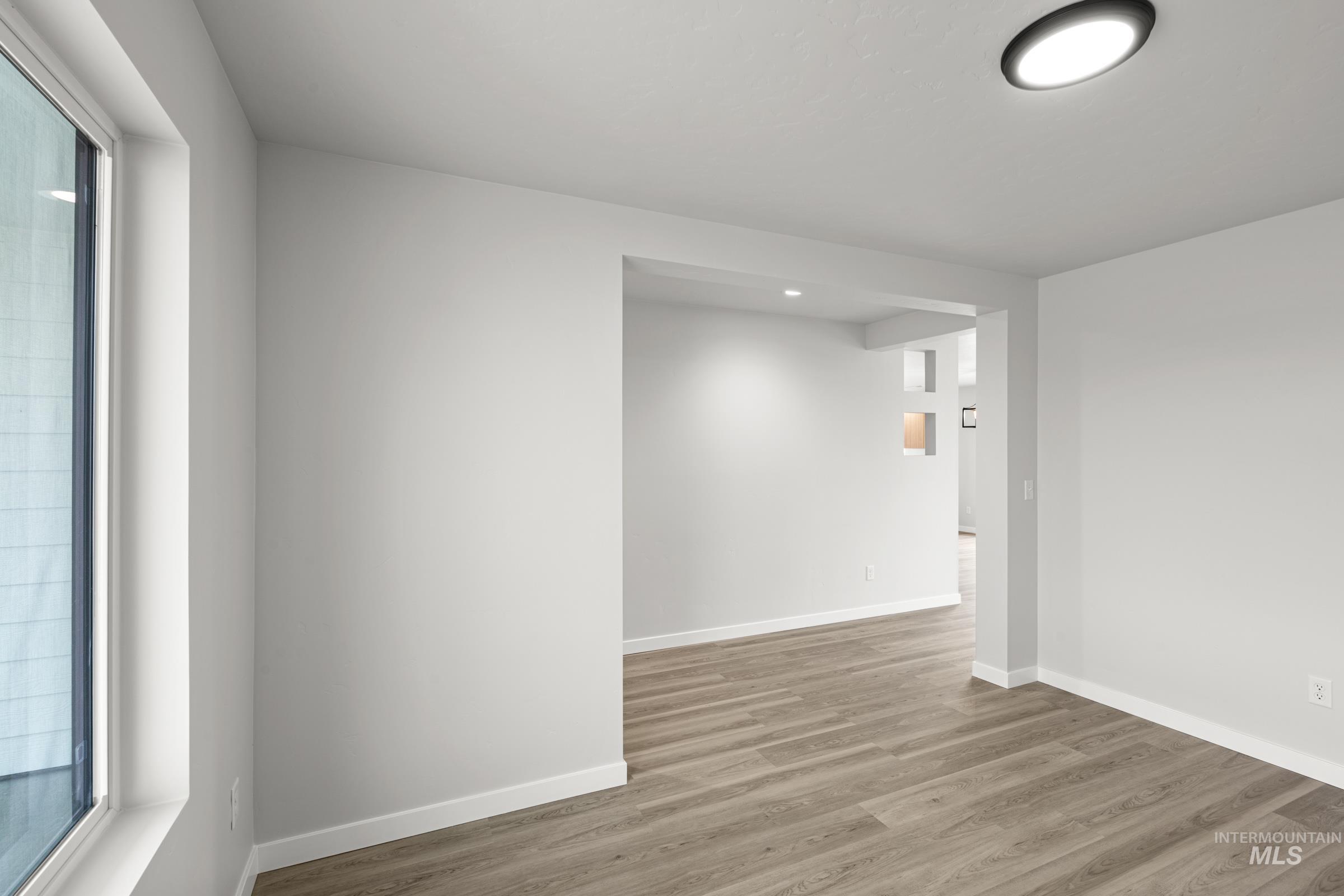 14056 Shiny Spruce Street Caldwell, ID 83607 - Photo 11 of 25 Open room with light gray walls, wood-finish flooring, a contemporary flush-mount ceiling light, and a large window