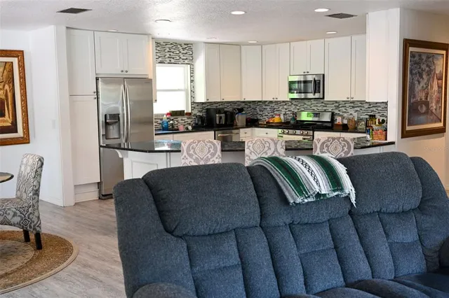 a kitchen with stainless steel appliances granite countertop a refrigerator a stove a sink a dining table and chairs with wooden floor