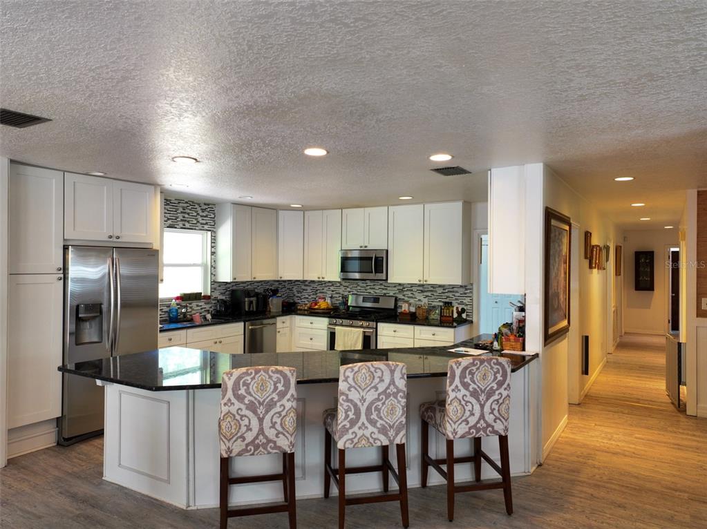 4501 Detour Road Haines City, FL 33844 - Photo 13 of 65 a kitchen with stainless steel appliances granite countertop a dining table chairs refrigerator and sink