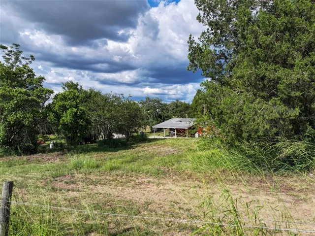 a view of a big yard with lots of green space and lake view in back