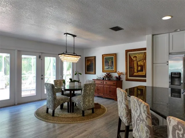 a dining room with wooden floor a chandelier a glass table and chairs