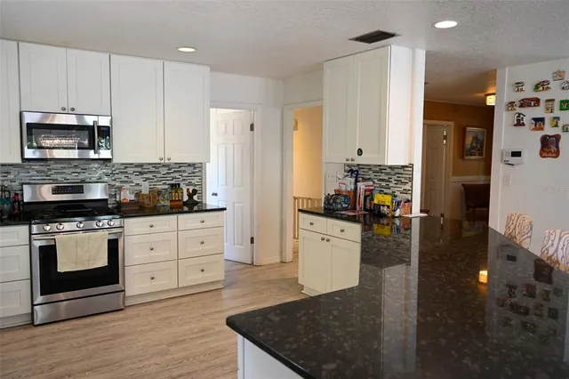 a kitchen with stainless steel appliances kitchen island granite countertop a stove a sink and a refrigerator
