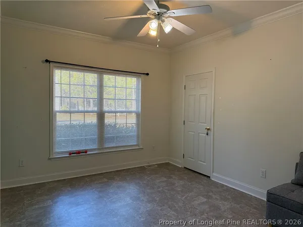 an empty room with wooden floor fan and windows