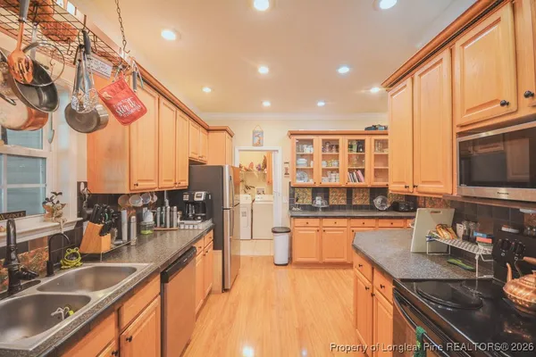 a kitchen with stainless steel appliances granite countertop a refrigerator a stove and a sink with wooden floor