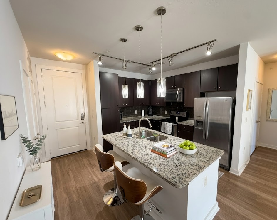 1900 Barton Springs Road, Unit 3036 Austin, TX 78704 - Photo 2 of 19 Granite counters and dark wood cabinetry define this modern kitchen, offering both style and function.