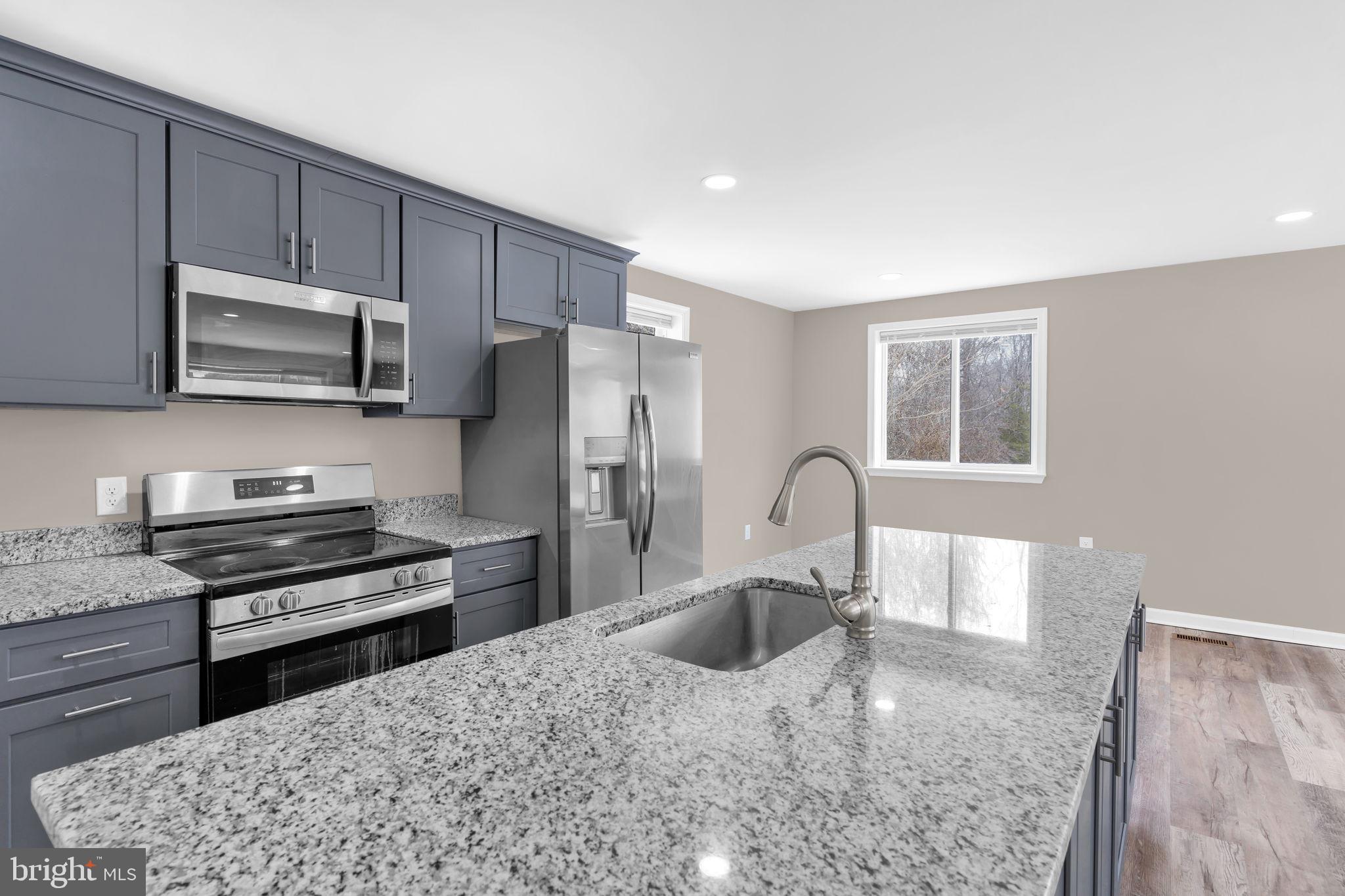383 Sollers Wharf Road, Unit A Lusby, MD 20657 - Photo 4 of 16 a kitchen with granite countertop a stove a sink and a refrigerator