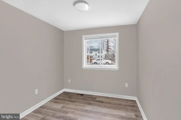 an empty room with wooden floor and window