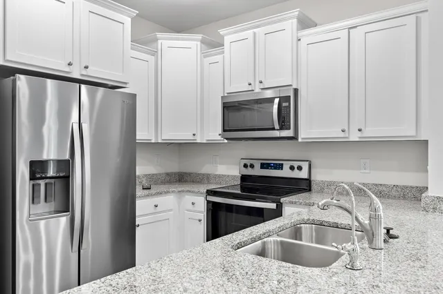 a kitchen with stainless steel appliances granite countertop a sink refrigerator and cabinets