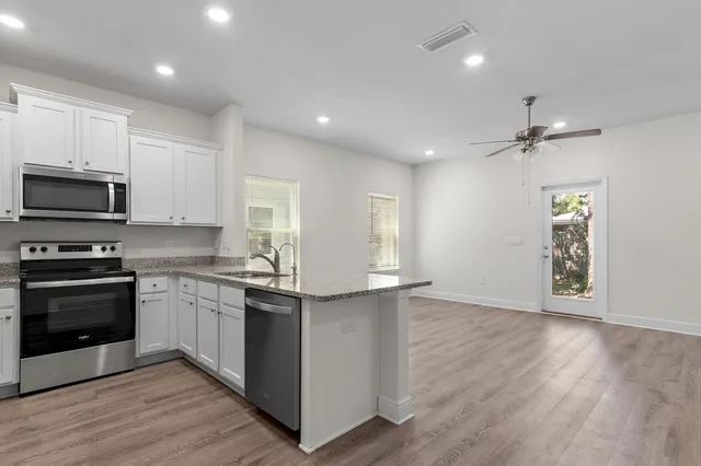 an empty room with wooden floor fan and windows