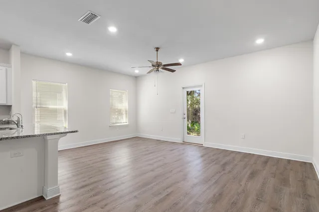 a view of a big room with wooden floor and a kitchen