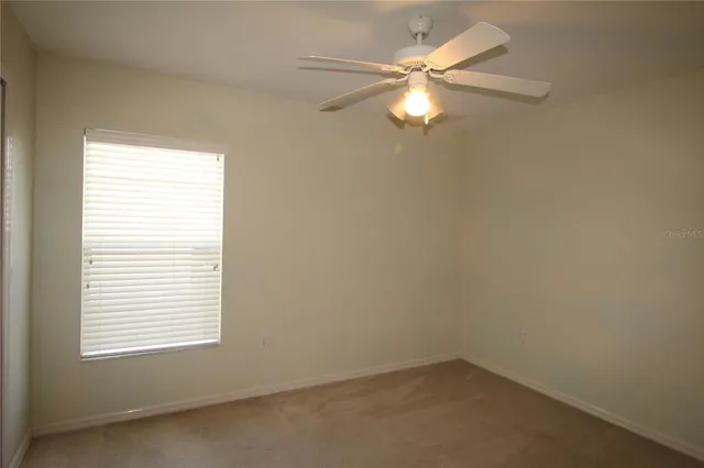 an empty room with a window and a fan