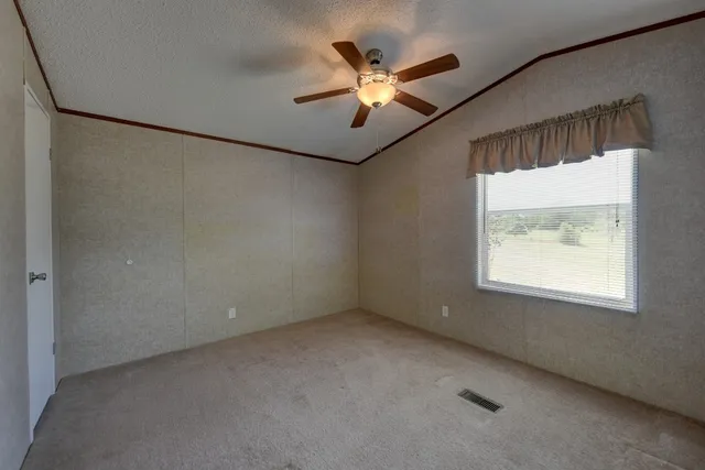 an empty room with windows and fan