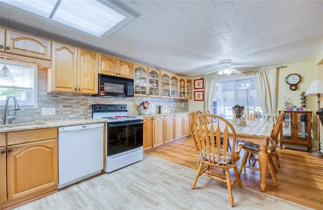 a kitchen with stainless steel appliances granite countertop a stove top oven a sink a dining table and chairs with wooden floor