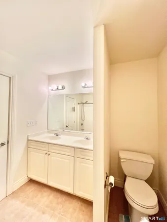 a bathroom with a granite countertop toilet sink and mirror