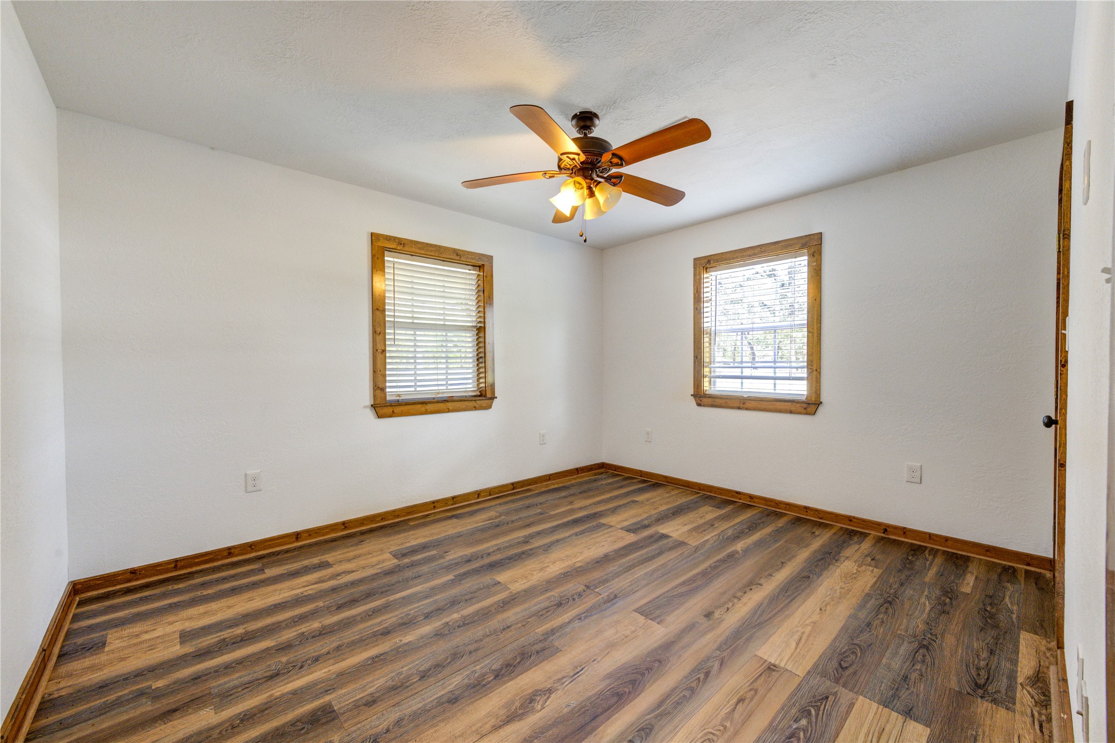 8805 Sun Oil Road Brenham, TX 77833 - Photo 34 of 50 Bright and inviting bedroom featuring rich wood flooring, dual windows for natural light, and a stylish ceiling fan for comfort.