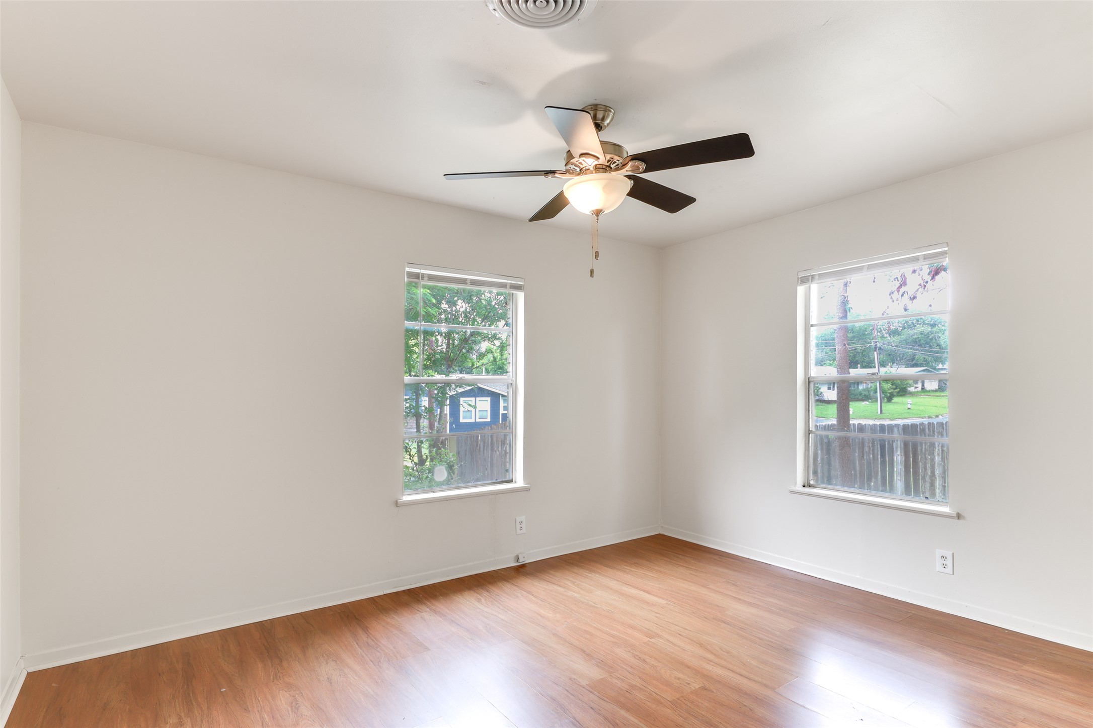 1800 Rhodes Road Austin, TX 78721 - Photo 7 of 14 an empty room with wooden floor chandelier fan and windows