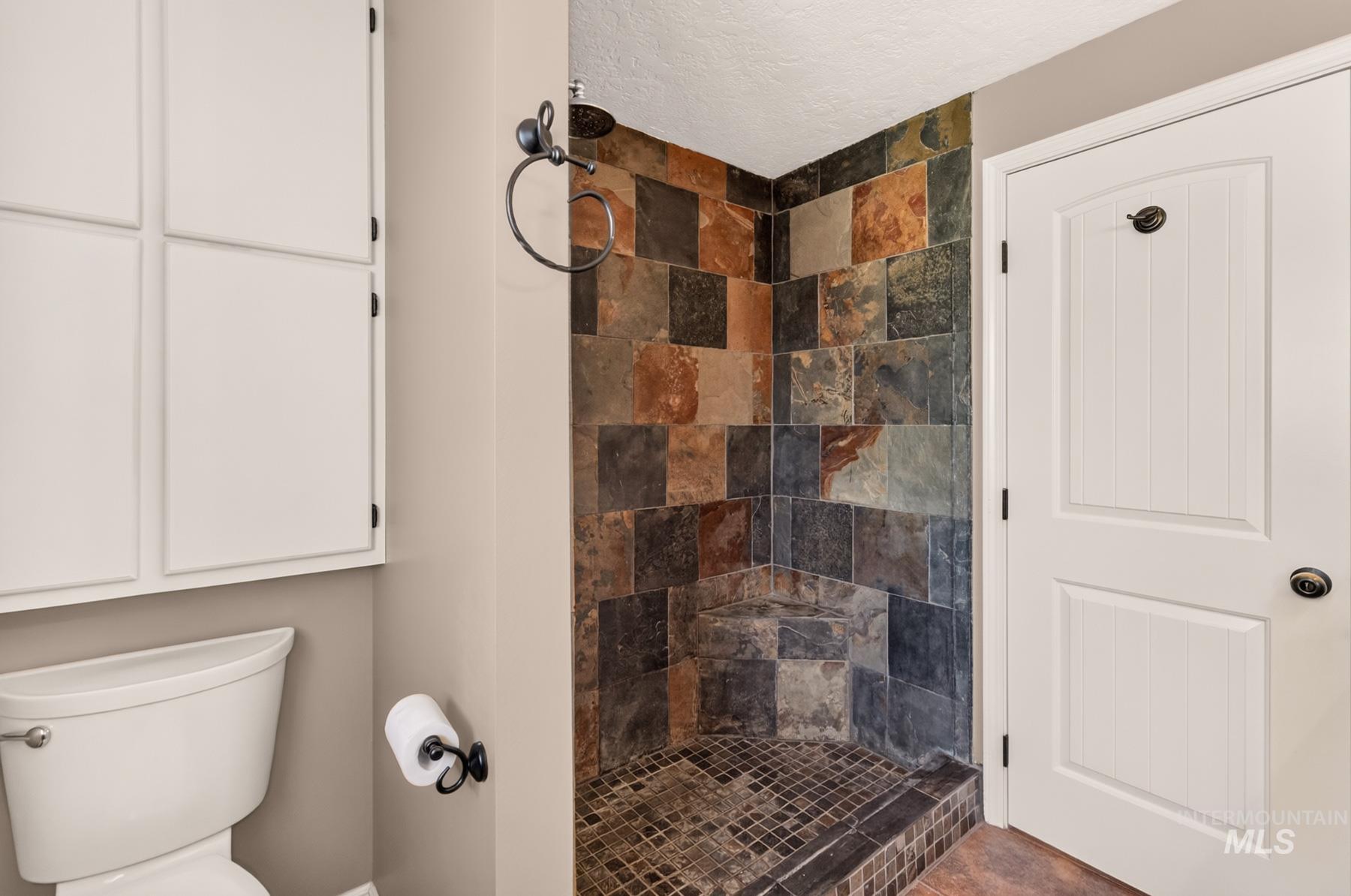 9622 Delaware Street Boise, ID 83709 - Photo 30 of 48 Shower featuring multi-toned natural stone tile walls and a built-in corner bench