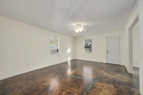 an empty room with a ceiling fan and windows