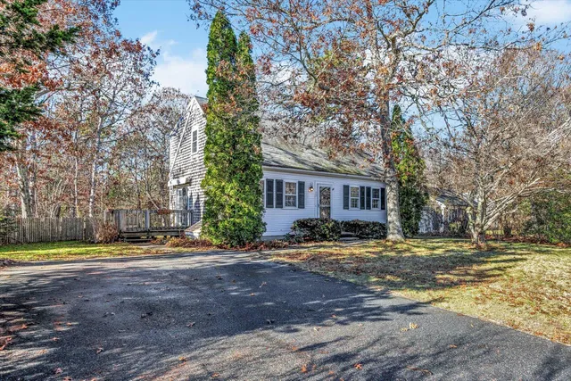 a view of a house with a yard and large trees