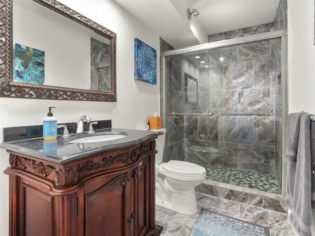 a bathroom with a sink a toilet a mirror and shower