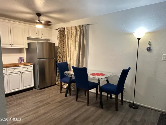 a kitchen with stainless steel appliances granite countertop a dining table chairs refrigerator and sink