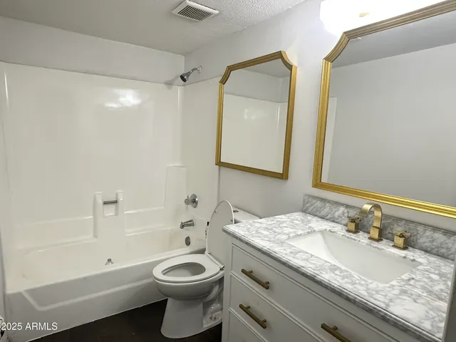 a bathroom with a granite countertop toilet a sink and a mirror