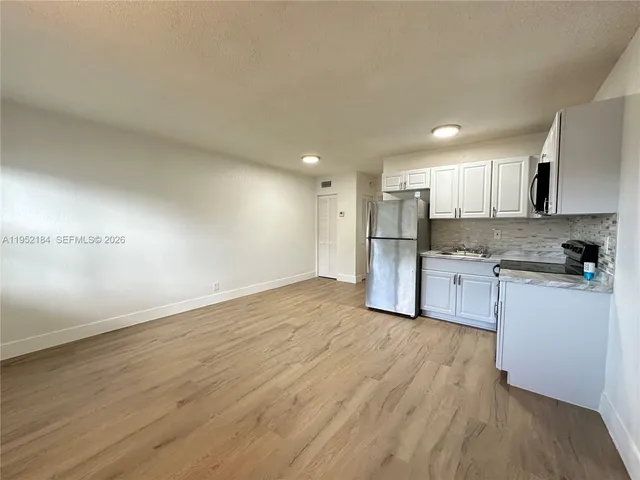 a kitchen with granite countertop a refrigerator and a stove top oven
