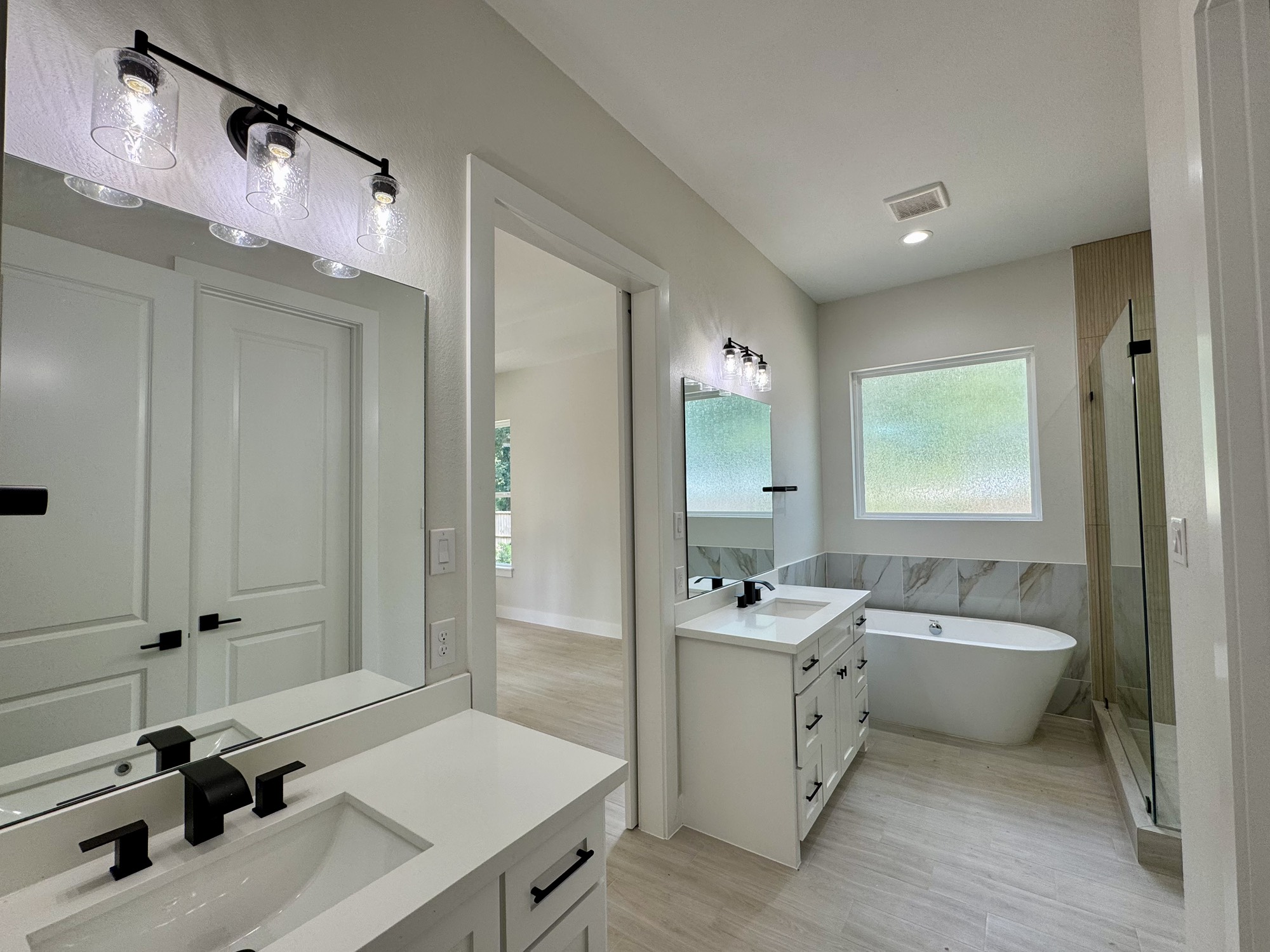 27710 Colapis Drive Splendora, TX 77372 - Photo 29 of 49 a bathroom with a double vanity sink a mirror and a bathtub