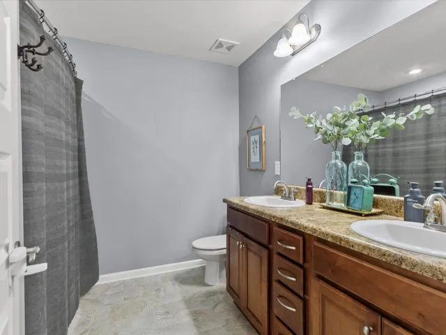 a bathroom with a granite countertop sink a toilet a mirror and shower