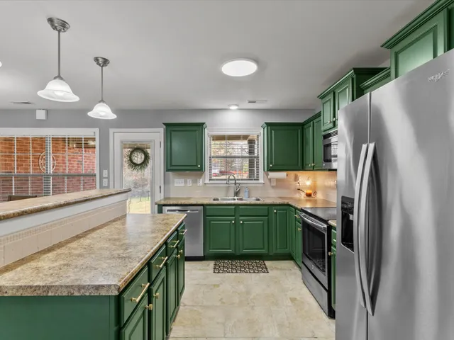 a kitchen with stainless steel appliances granite countertop a sink refrigerator and cabinets