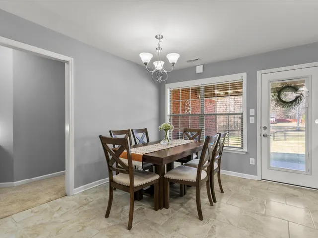 a view of a dining room with furniture a chandelier and a window