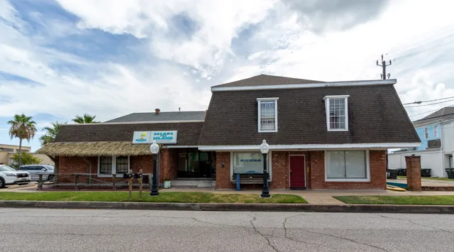 a view of a house with a yard and table and chairs under an umbrella