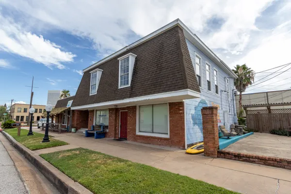 a view of a white house with large windows and a table and chairs