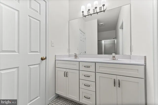 a bathroom with a double vanity sink a mirror and shower