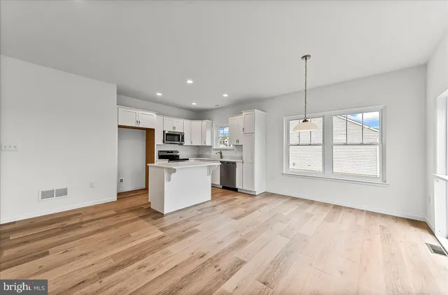 a kitchen with stainless steel appliances kitchen island sink refrigerator and cabinets