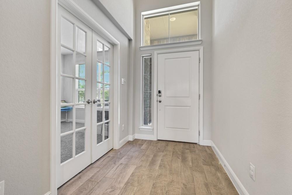 1112 Croxley Way Justin, TX 76247 - Photo 2 of 18 Entryway featuring wood-finish flooring, a white paneled entry door with sidelight, and a transom window